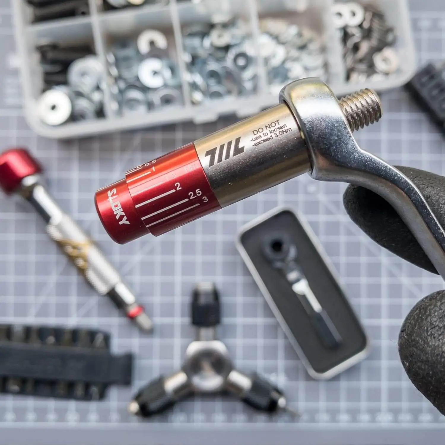 Gloved hand twisting the 711L Torque Driver on a Leatherman multitool, protecting your tools by achieving desired tightness without over‑torquing